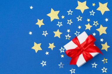 Güzel mavi bir arka planda altın yıldızlı Noel hediyesi kutusu. Düz yatıyordu. Üst görünüm