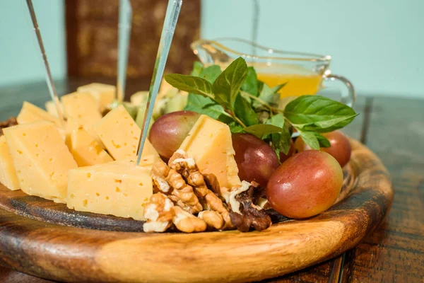 Cheese platter on a wooden plate on a large wooden table