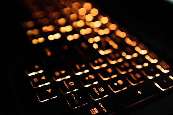 Computer keyboard with Russian and English layout. Backlit by neon light.