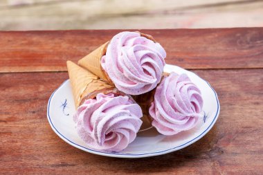 Waffle külahında ev yapımı vişneli marshmallow ve ahşap masada çikolata.