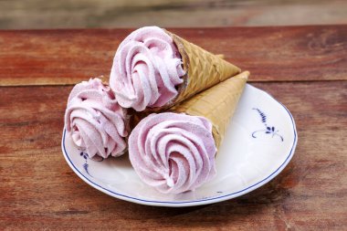 Waffle külahında ev yapımı vişneli marshmallow ve ahşap masada çikolata.