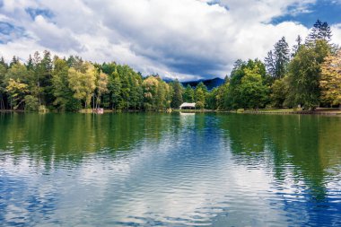 Bulutlar bir dağ gölünün suyuna yansıyor.