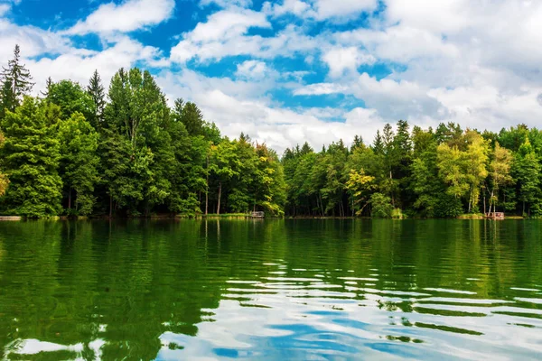 Bulutlar bir dağ gölünün suyuna yansıyor.