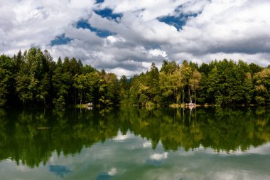 Bulutlar bir dağ gölünün suyuna yansıyor.