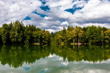 Bulutlar bir dağ gölünün suyuna yansıyor.
