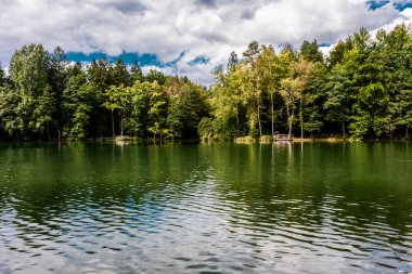 Bulutlar bir dağ gölünün suyuna yansıyor.