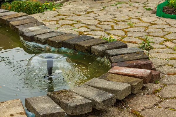 A small fountain in an artificial pond.