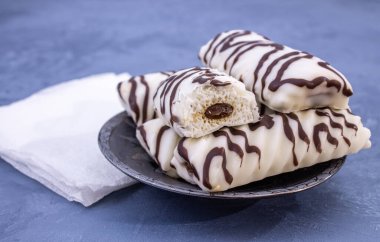 Tabakta çikolata jöleli dört beyaz kremalı pasta. Mavi arkaplanda yakın plan.