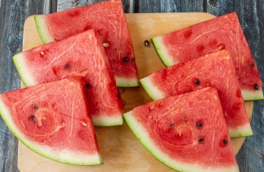 Kesme tahtasında altı tane üçgen karpuz dilimi. Üst görünümü kapat.