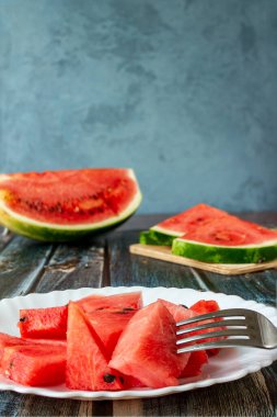 Kırmızı karpuz, yakın plan bir tabakta küçük dilimler halinde kesilmiş. Mavi arkaplan bulanık.