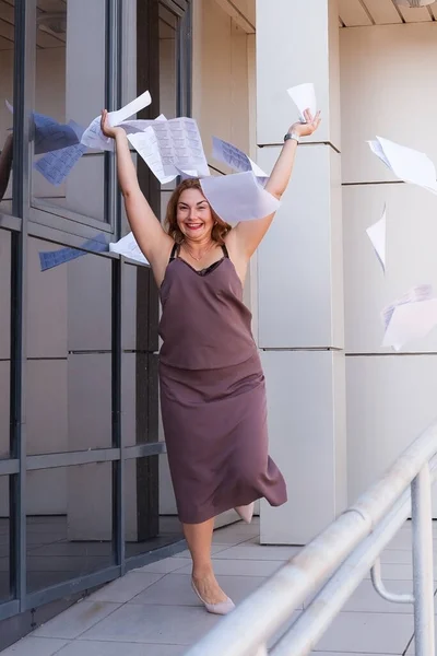 a busy young woman with papers in her hands, a happy business woman tosses the papers up
