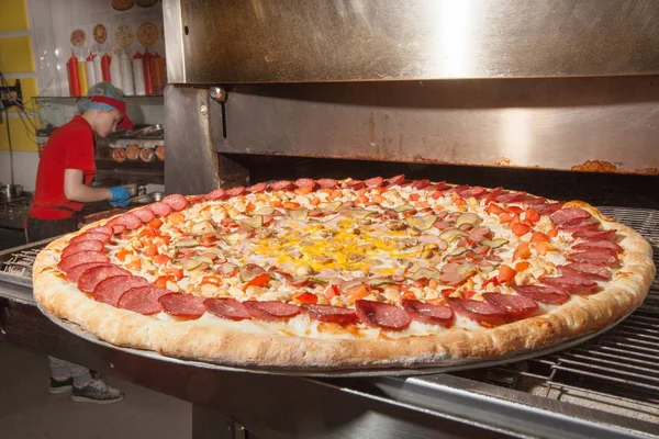 very large pizza, cooking pizza, pizza oven