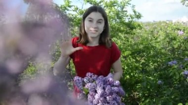 Güzel genç kız güneşli bir günde yüzünü bir buket çiçekle kaplayarak eğleniyor.