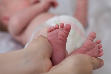 Ebeveyn yeni doğan bebeğin küçük ayaklarını nazikçe elinde tutar. Anne ve Çocuk. Anneliğin çok güzel kavramsal bir görüntüsü. Mutlu aile kavramı. Kopyalama alanı