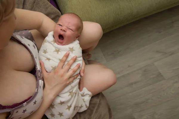 Um bebê recém-nascido bonito encontra-se em um envoltório em seu colo mães e boceja docemente. O miúdo tem uma semana. Vista de cima. Espaço de cópia — Fotografia de Stock