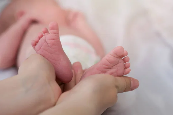 Детские ноги в родительских руках. Мать и ее ребенок. Маленькие розовые ножки новорожденного. Счастливая семья и расставание. Copyspace — стоковое фото