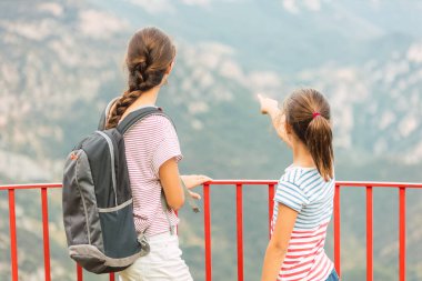 İki kız kardeş dağlara güzel bir yerden bakıyor.