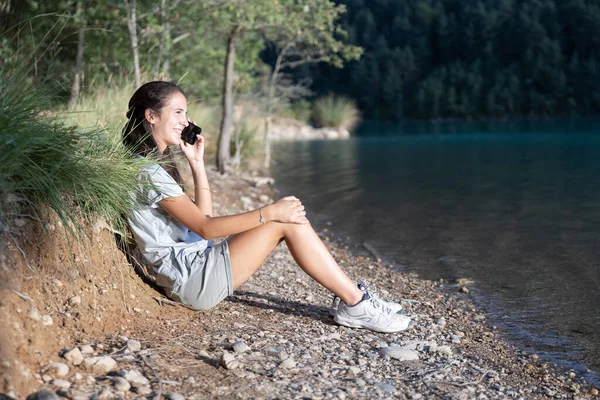 Chica Sonriente Hablando Por Teléfono Sentada Junto Lago Por Tarde — Foto de Stock