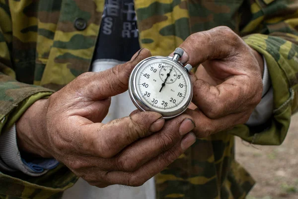 silver stopwatch in the hands of a worker. hands of hard workers.