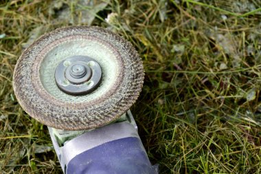 Disk zımpara makinesi çimlerin üzerinde yatıyor.