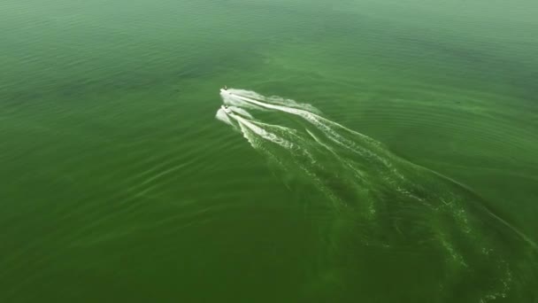 Dos personas en motos acuáticas corren a través del agua verde con pequeñas olas. Disparos con drones. Vista desde arriba — Vídeo de stock