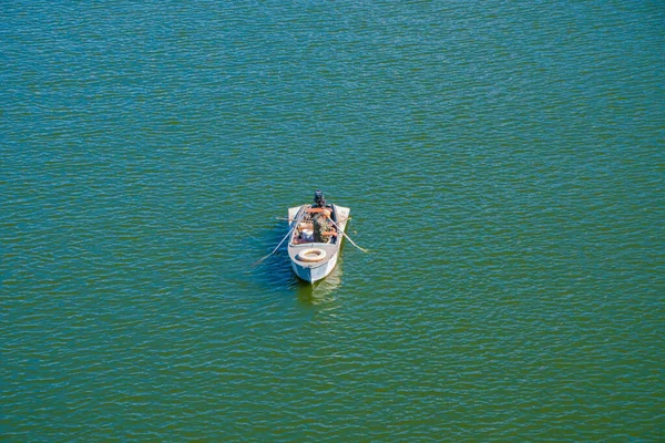 Lone fisherman in military uniform catches fish from a boat in the middle of the river — Stock Photo, Image