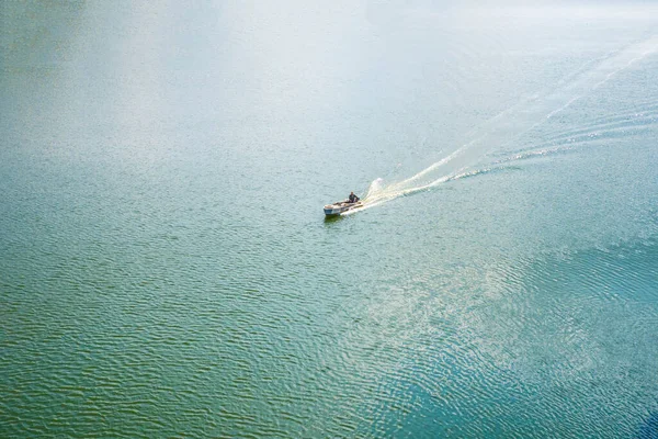 Самотній рибальський човен пливе серед блакитного моря. Вид зверху — стокове фото