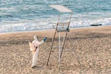 Barbelona 'da. İspanya... 22 Ağustos 2020 'de. Şehir konseyinin temizlik ekibinin bir üyesi, gün doğmadan önce Barceloneta plajında cankurtaran koltuğunu dezenfekte eder..