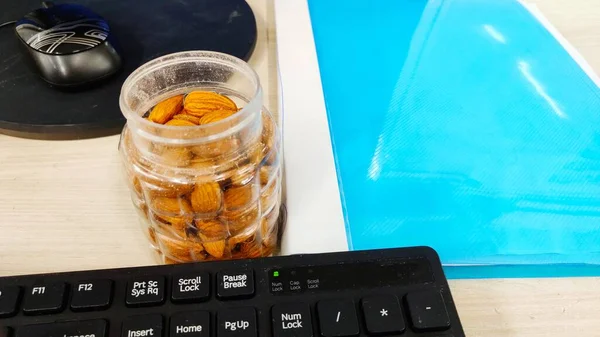 Mandel nöt på kontoret Bord och i transparent låda för hälsosamma snacks diet plan på ljus färg bakgrund med utrymme för text Selektiv Fokus. — Stockfoto