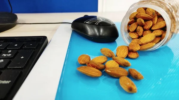 Bademler ofis masasında fındık ve sağlıklı abur cuburlar için şeffaf kutuda açık renk arkaplan üzerine diyet planı ve metin Seçici Odaklanma için boşluk.