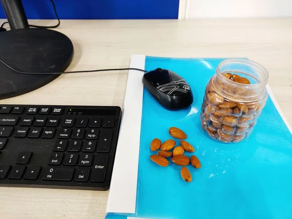 Mandel nöt på kontoret Bord och i transparent låda för hälsosamma snacks diet plan på ljus färg bakgrund med utrymme för text Selektiv Fokus. — Stockfoto