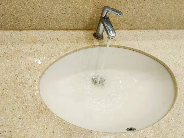 Отходы воды из крана в раковине в ванной комнате — стоковое фото