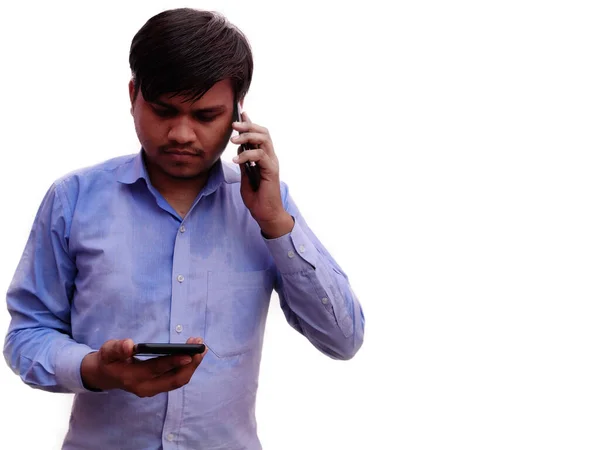 Hücrede konuşan ve yazan iki cep telefonu kullanan bir adam var. Mavi elbiseli Hintli adamlar beyaz arka planda izole edilmiş.