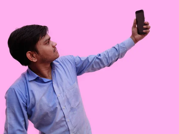 Cep telefonundan selfie çeken adam pembe arka planda izole edilmiş.