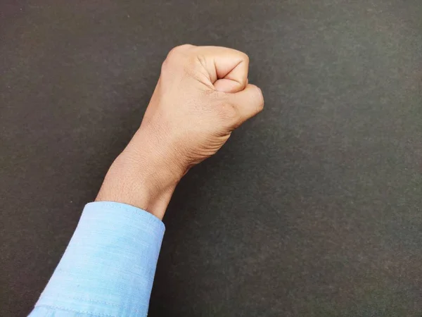 Ручний кулак людини з синьою сорочкою в повітрі на чорному тлі. Революція, смілива, чоловіча концепція. — стокове фото