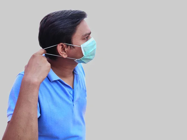 Hombre con máscara facial tirando de cuerdas de marca para colocarlo sobre las orejas —  Fotos de Stock
