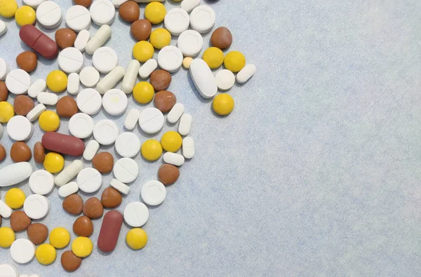 Tabletas y pastillas se extienden sobre fondo azul con espacio de copia y enfoque selectivo — Foto de Stock