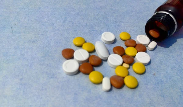 Fles pillen op blauwe achtergrond voor genezing van ziekte, tabletten verspreid op papier met ruimte voor tekst — Stockfoto