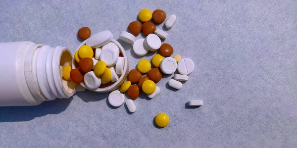 Fles pillen op blauwe achtergrond voor genezing van ziekte, tabletten verspreid op papier met ruimte voor tekst — Stockfoto