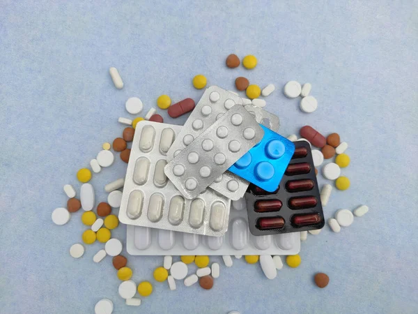 Tabletki i tabletki rozłożone na niebieskim tle z miejsca na ksero i selektywną ostrość — Zdjęcie stockowe