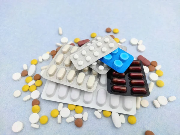 Tabletten en pillen verspreid over een blauwe achtergrond met kopieerruimte en Selectieve Focus — Stockfoto