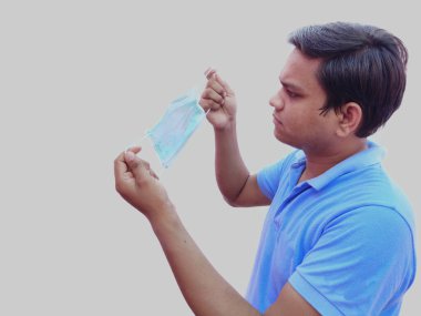 Yüz maskesi tutan adam Corona virüsüne karşı korunmak için takacak.