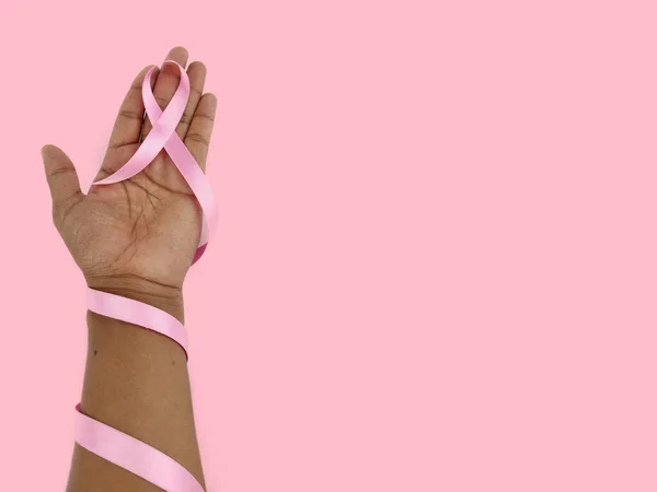 Pink ribbon breast cancer awareness symbol kept between hands as Support and care Concept