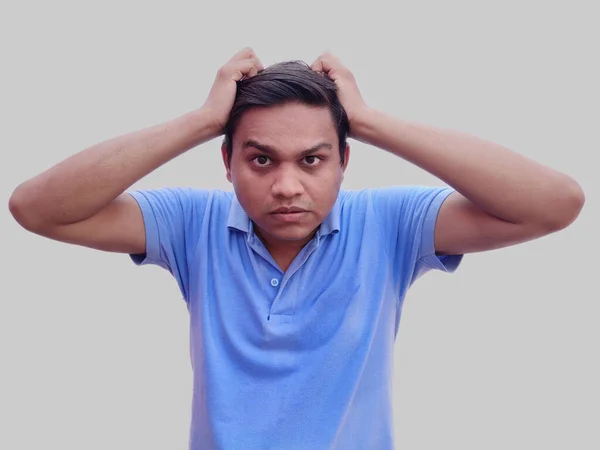 Emotional Indian man pulling hair in despair on grey background — Stock Photo, Image