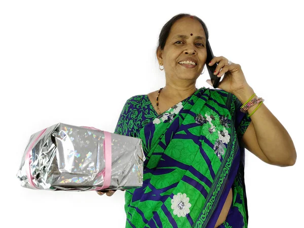 印度妇女在家里拿着礼物盒，在电视或电话中庆祝生日或周年纪念日. — 图库照片