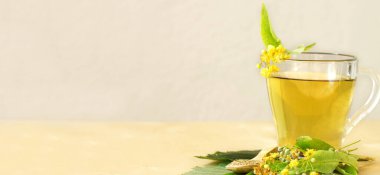 Açık arkaplanda çiçek açan Tilia (ıhlamur ağacı, basswood) ile bir fincan taze bitki çayı. Yan görüş. Kapatın. Mesaj için yer var. Pankart