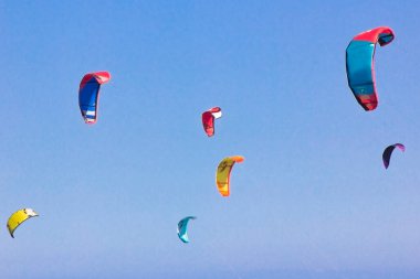 Güzel mavi gökyüzüne karşı uçurtma sörfü yapmak. Gökyüzünde bir sürü uçurtma silueti var. Seyahat konsepti. Güzellik dünyası. Su sporları. Rüzgar severler. Uçurtma tipi. Uçurtma rotası