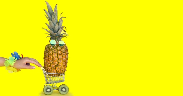 Summer shopping and fruit delivery. A woman hand with hawaiian garland holding and pushing a shopping trolley with a pineapple with sunglasses on yellow background. Space for text.