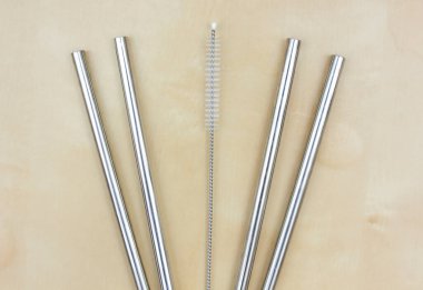 Gümüş metal pipetler ve temizlik fırçası düz bir zemin üzerinde yatıyordu. Üst görünüm sıfır atık çelik kokteyl samanı