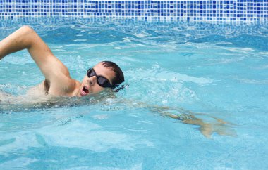Yüzme gözlükleriyle havuzda yüzen bir adam. Yarış için havuzda yüzen sporcu. Profesyonel erkek su sporu erişkinleri dışarıda suda kardiyo yapıyor..